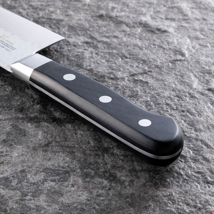 Close-up of the handle of the Kai Seki Magoroku Hammered Santoku Knife 145mm, featuring a polished black wooden grip secured with three rivets for durability and a comfortable hold.