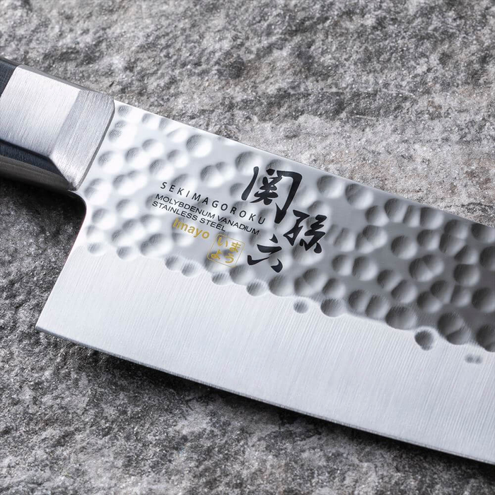 Close-up of the Kai Seki Magoroku Hammered Santoku Knife 145mm, highlighting the intricate hammered texture and the engraved logo on the blade