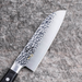 Side view of the Kai Seki Magoroku Hammered Santoku Knife 145mm, emphasizing the sharp blade edge and polished steel bolster.