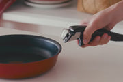 A T-fal Ingenio frying pan with handle attached serving paella, next to a saucepan of pasta on a dining table.