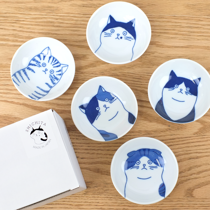The Shichita Mino Yaki Cat 5-piece side bowl set, showing five bowls with different cat illustrations displayed next to their yellow gift box.