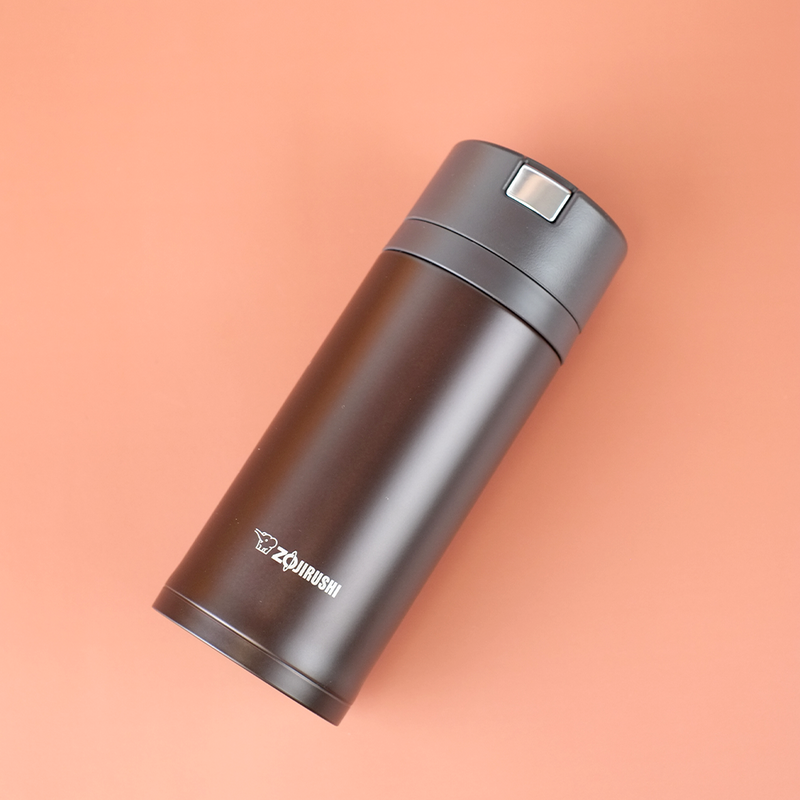 A sleek black Zojirushi SM-XB36 vacuum insulated flask positioned diagonally on a soft peach background.