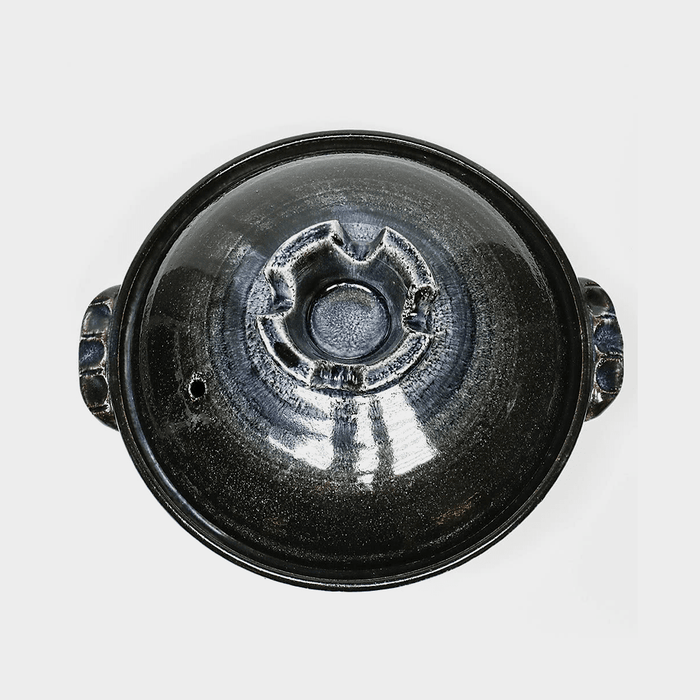 Elegant black clay cooking vessel with a unique lid design, showcasing Japanese craftsmanship.