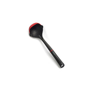 The Happycall Edge ladle, showing its black polyamide body, distinctive red silicone edge, and interior measurement markings, angled on a white background.
