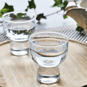A styled lifestyle photo of two Toyo Sasaki sake glasses filled with clear liquid, presented on a wooden tray to show a serving suggestion.