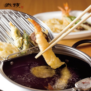An appetising close-up of a golden-brown tempura shrimp being lifted with chopsticks from the hot oil of the Yoshikawa deep fryer, while other pieces drain on the integrated wire rack.
