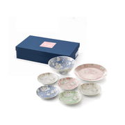 The Aito Mino Yaki Uno Chiyo Blossom 7-piece dinnerware set, including a large bowl, large plate, and five small plates in assorted colours with cherry blossom designs, displayed next to its blue gift box.