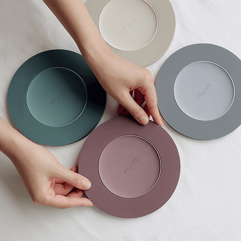 A collection of four Dogado 2-in-1 silicone coasters and table mats in various colours, demonstrating the versatile design.

