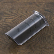 The Kai Seki Magoroku Diamond and Ceramic Knife Sharpener shown with its transparent protective cover on, resting on a dark wooden surface.
