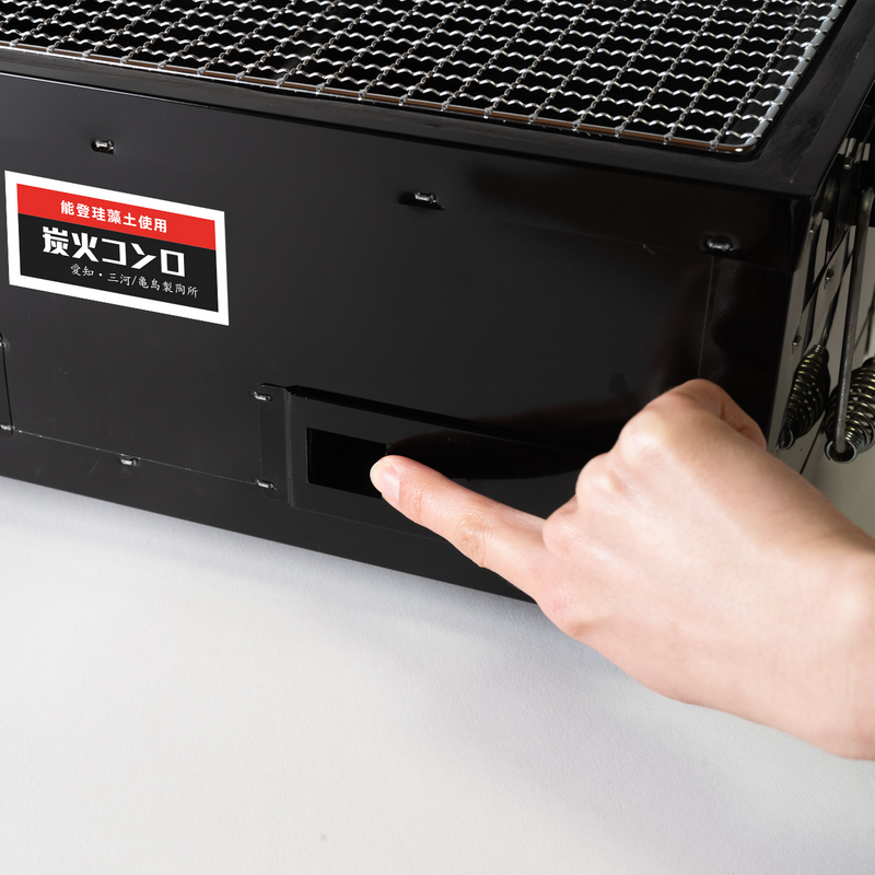 Adjusting the airflow by opening the ventilation window on the side of the Mikawa konro grill.

