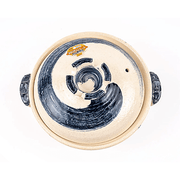 A top-down view of a Shigaraki Yaki donabe lid, highlighting the expressive, swirling blue brushstroke pattern.

