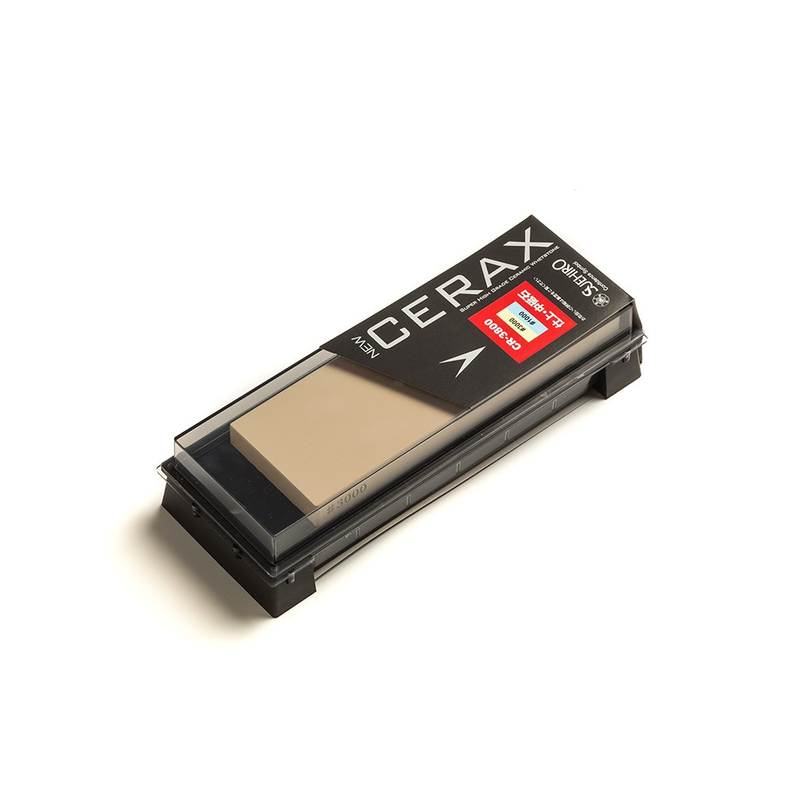 The Suehiro NEW CERAX CR-3800 two-sided whetstone shown inside its combination storage case and sharpening base, with a transparent lid.
